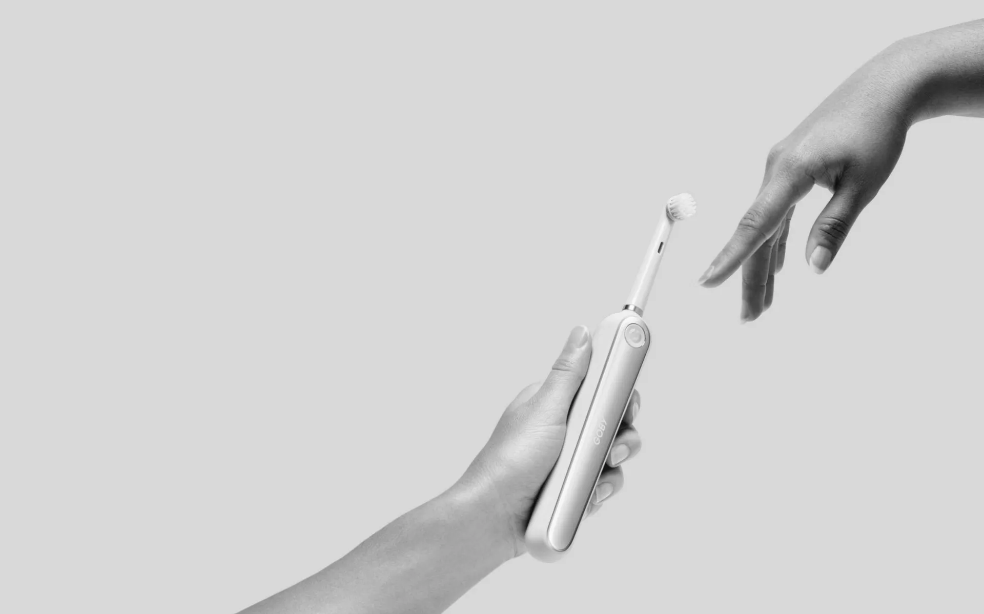 Cepillo dental eléctrico blanco sostenido en la mano sobre fondo claro