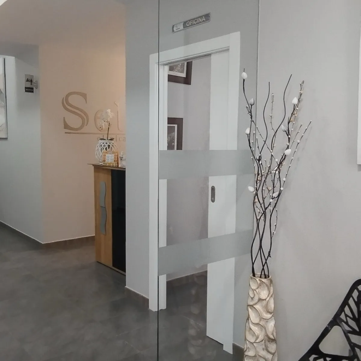 Pasillo acristalado de Clínica Dental Seijo que da acceso al mostrador de recepción